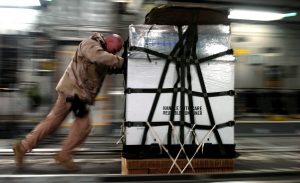 Worker pushing cargo on pallet in warehouse